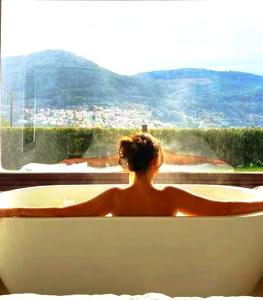 a woman sitting in a bath tub looking out a window at Casa Nueva de Vigo Rural Mos con Jacuzzi y chimenea in Mos
