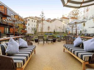 een patio met stoelen, tafels en parasols bij Mercure Porto Centro Aliados in Porto