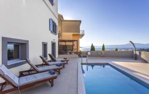 ein Swimmingpool mit Liegestühlen neben einem Haus in der Unterkunft Villa Castel Muschio by Villas Guide in Omišalj