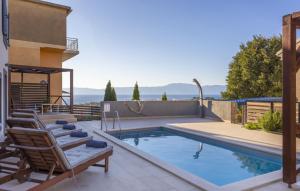 ein Swimmingpool mit Stühlen neben einem Haus in der Unterkunft Villa Castel Muschio by Villas Guide in Omišalj