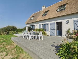 a wooden deck with chairs and a table in front of a house at Longère - 10 personnes - Vue mer in Tréguennec
