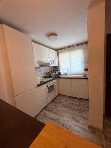 a small kitchen with white cabinets and a sink at Residencial Bajo con jardín y jacuzzi privado Calahonda Royale in Cabopino