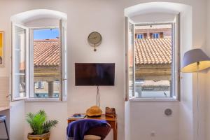 a living room with two windows and a flat screen tv at Studio Le Paolina à quelques mètres de la plage in LʼÎle-Rousse