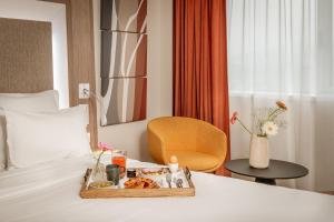 a tray of food on a bed in a hotel room at Novotel Lyon Centre-Confluence Bord de Saone in Lyon