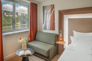 a bedroom with a bed and a chair and a window at Novotel Lyon Centre-Confluence Bord de Saone in Lyon