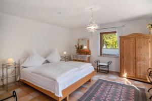 a bedroom with a bed with white sheets and a mirror at Naturferienwohnung Am Lautergarten in Indelhausen
