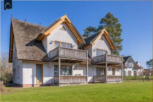 a large white house with decks on a lawn at Ferienwohnung Fisch in Loddin