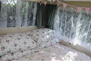 a bedroom with a bed with pillows and a window at 1 Bed Caravan Sleeps 2 - Parking Garden Pets in Lizard