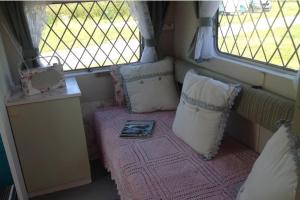 a room with a bed with pillows and a window at 1 Bed Caravan Sleeps 2 - Parking Garden Pets in Lizard