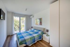 a white bedroom with a bed and a window at Summer Villas in Lignano Sabbiadoro