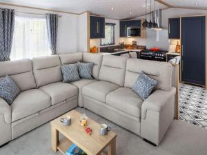 a living room with a large couch and a kitchen at Wilksworth Caravan Park in Wimborne Minster