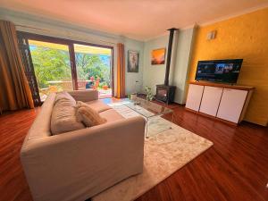 a living room with a white couch and a television at Nudist Naturist Port Nature Sandy Bay in Cape Town