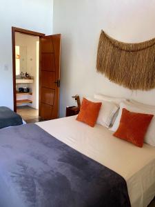 a bedroom with a bed with orange and white pillows at Divina Casa in Itacaré