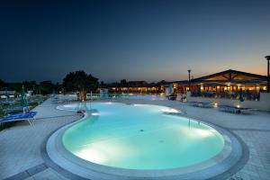 Una gran piscina en un patio por la noche. en Cala Fiorita, en Agrustos