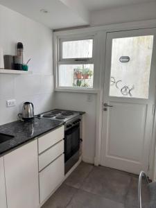 eine weiße Küche mit einem Herd und einem Fenster in der Unterkunft Departamento Roca in La Porteña