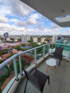 a balcony with two chairs and a table on a building at Luxury 2 Bedroom "Wake Up in the Sky" Best Views & Location in Asuncion in Asuncion