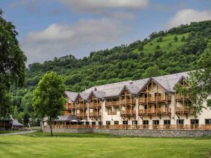 a large building with a mountain in the background at Mercure Peyragudes Loudenvielle Pyrénées in Loudenvielle