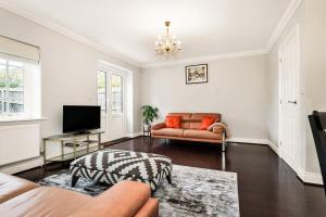 a living room with a couch and a television at Chic 3Bed House & Garden Near Shelford High Street in Trumpington
