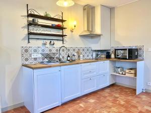 a kitchen with white cabinets and a counter top at Porterie du château Clim Wifi Terrasse Bord Loire in Gennes