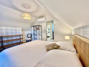 a bedroom with a large white bed and a clock at Porterie du château Clim Wifi Terrasse Bord Loire in Gennes
