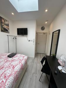 a bedroom with a bed and a desk and a television at The Cosy one in Sutton