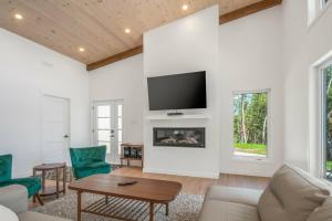 Elle comprend un salon avec une cheminée et une télévision murale. dans l'établissement Chalet à louer au bord d'un lac avec spa, à La Baie
