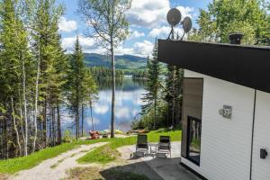 une maison avec des chaises et une vue sur le lac dans l'établissement Chalet à louer au bord d'un lac avec spa, à La Baie