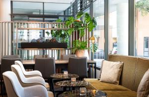 ザルツブルクにあるLeonardo Hotel Salzburg City Centerのテーブルと椅子と窓のあるレストラン