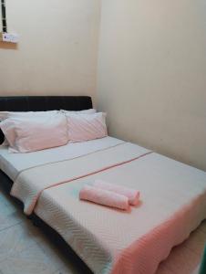 a bed with two pink towels on top of it at Kirana Homestay Langkawi in Pantai Cenang