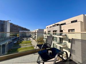a balcony with two chairs and a view of a city at Sunrise Apartments - Onix Pipera in Bucharest