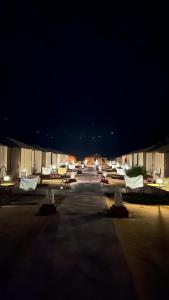 梅尔祖卡Oasis Desert Luxury Camp的夜间停车场里的一组椅子和桌子