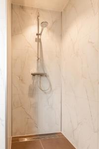 a shower in a bathroom with white marble walls at Natuur Villa met Hottub & Sauna | 4 personen - Resort Valley in Wekerom