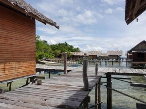 a wooden dock next to a building and water at Parfray Homestay Raja Ampat in Airborei