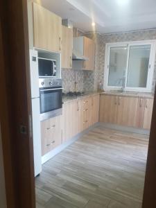 a kitchen with wooden cabinets and a white appliance at S2 lux jardin carthage in Tunis