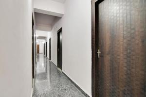 a hallway with white walls and a wooden door at Hotel O Kasturi And Banquet Hundur Halt in Kānke