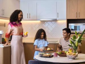 a woman holding a plate of food in a kitchen at Aparthotel Adagio Dubai Deira in Dubai