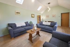a living room with two blue couches and a table at Host & Stay - The Byres in Dipton +18 photos
