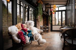 a group of stuffed teddy bears sitting on a chair at Hôtel-SPA Le Moulin De La Wantzenau - Strasbourg Nord in La Wantzenau