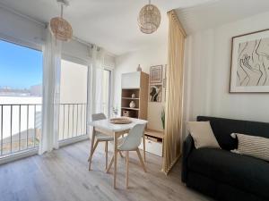 een woonkamer met een tafel en een bank bij Studio Design & Cosy - Accès Ile de Ré & Plages - WIFI PARKING GRATUIT in La Rochelle