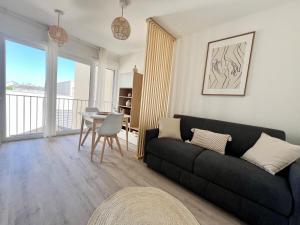 een woonkamer met een zwarte bank en een tafel bij Studio Design & Cosy - Accès Ile de Ré & Plages - WIFI PARKING GRATUIT in La Rochelle
