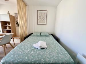een slaapkamer met een bed met een groen dekbed bij Studio Design & Cosy - Accès Ile de Ré & Plages - WIFI PARKING GRATUIT in La Rochelle