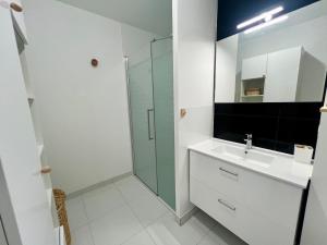 een witte badkamer met een wastafel en een douche bij Studio Design & Cosy - Accès Ile de Ré & Plages - WIFI PARKING GRATUIT in La Rochelle