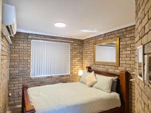 a bedroom with a brick wall and a bed at Tweebine Villas in Utakarra
