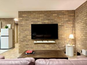 a living room with a brick wall with a tv at Tweebine Villas in Utakarra