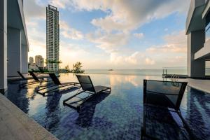 Tanjong TokongにあるPenang Beachfront Seaview Residencesの建物の前にスイミングプール(ラウンジチェア付)