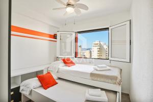 una camera da letto con un letto con cuscini arancioni e una finestra di Vista al Mar 10 Gandía a Playa de Gandia