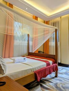 a bedroom with a bed with a canopy at Palm Gardens Guesthouse in Kampala