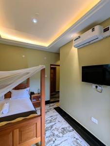 a bedroom with a bed and a flat screen tv at Palm Gardens Guesthouse in Kampala +130 photos