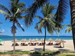 a beach with chairs and umbrellas and the ocean at Richico Apartments And Hotel in Da Nang