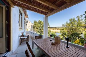 een houten tafel op een balkon met uitzicht op een rivier bij Casa Turquesa Pet-Friendly, Riverfront Home in Constância